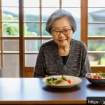 노인성 질환 예방 요양 - An elderly Japanese woman in her 70s wearing comfortable casual clothes and glasses, sitting at a co...